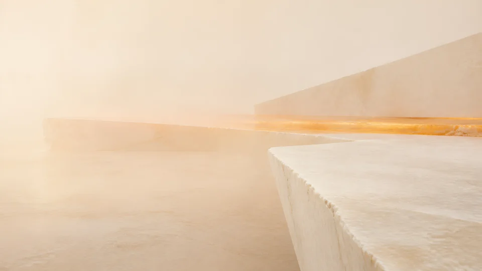 Low alabaster slabs collect a saffron heat seam inside a field of warm mineral air.