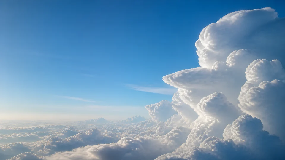 A sculptural cumulus system rises from a high cloud ocean into a desktop-safe cerulean shelf.