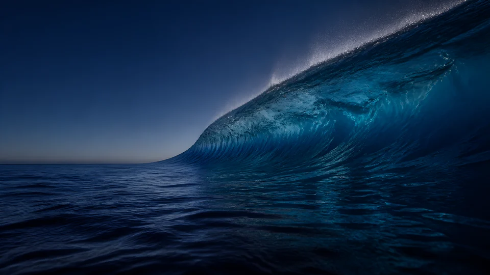 A monumental unbroken cobalt swell lifts at water level, carrying turquoise caustics beneath a silver ridge.