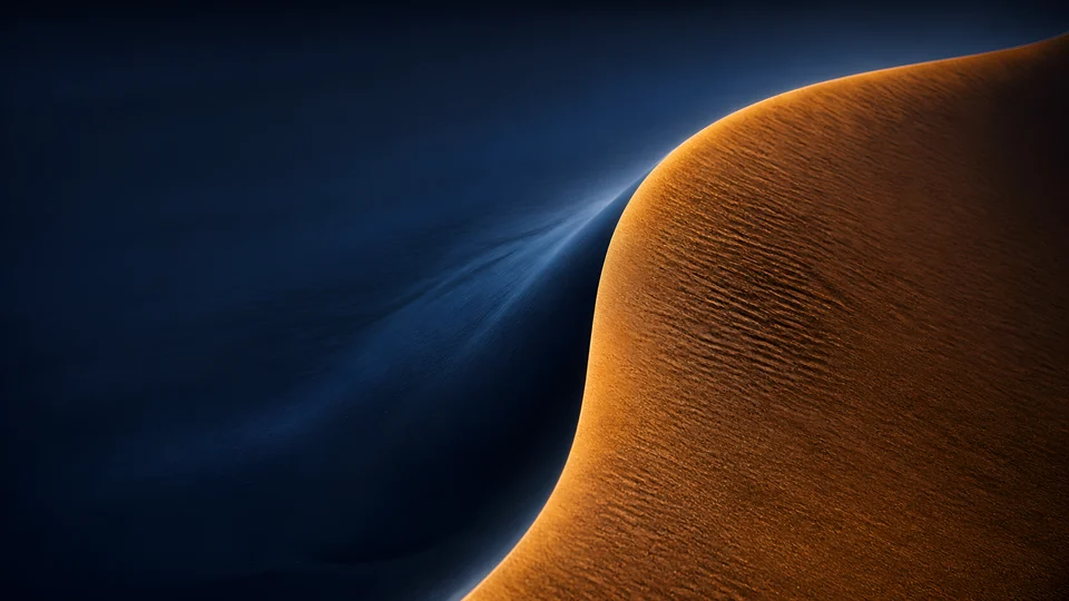 A crescent dune holds copper daylight and indigo moon-shadow on opposite faces of one razor ridge.